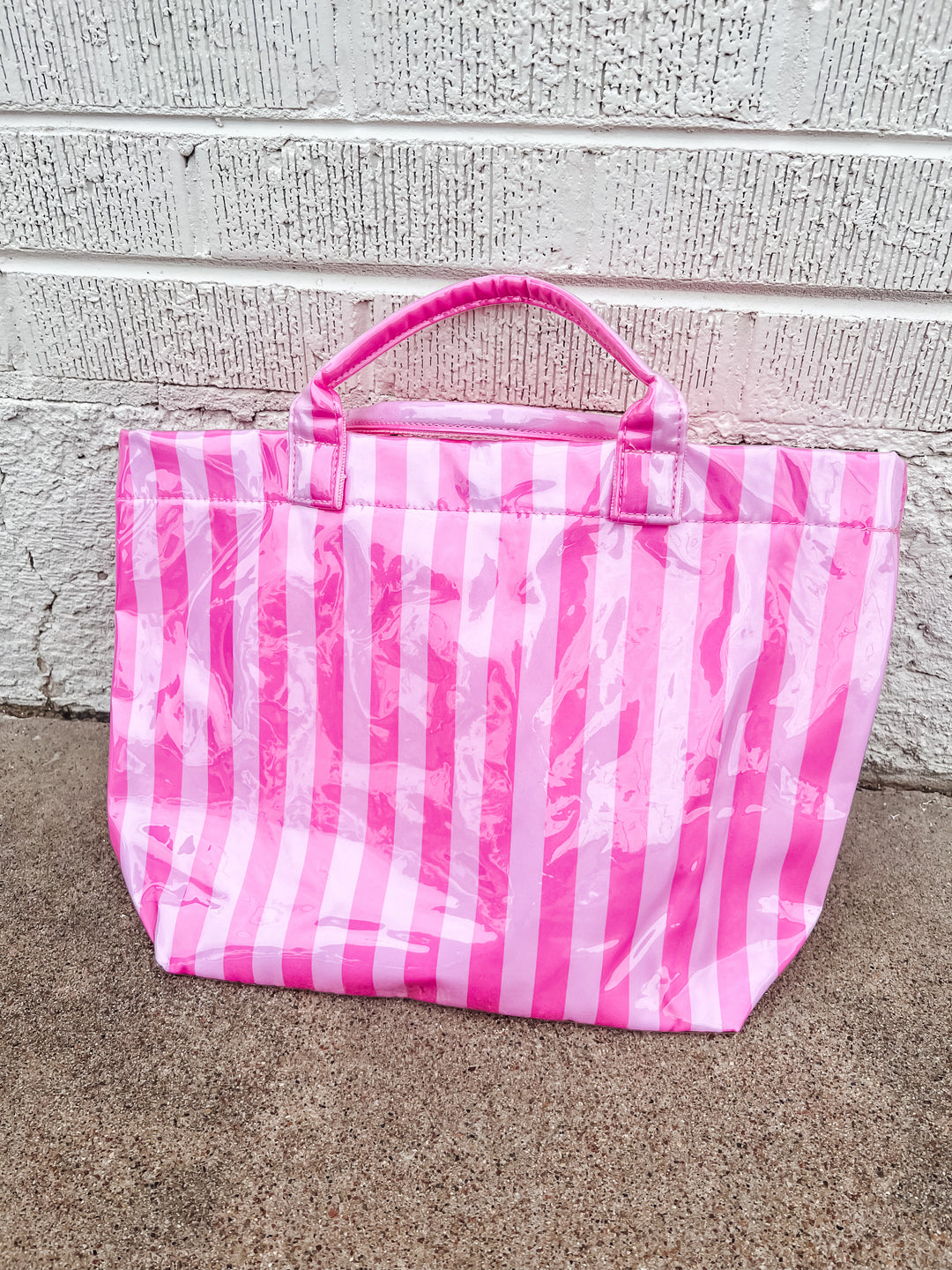 pink and white striped waterproof beach bag on a concrete surface 