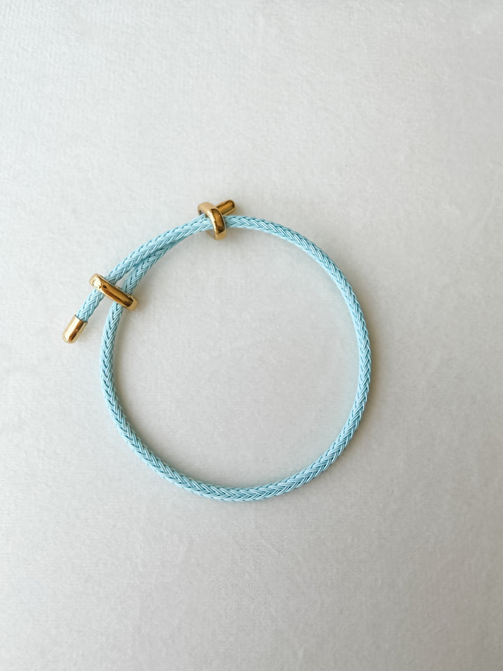 Light blue adjustable paracord bracelet with gold accents