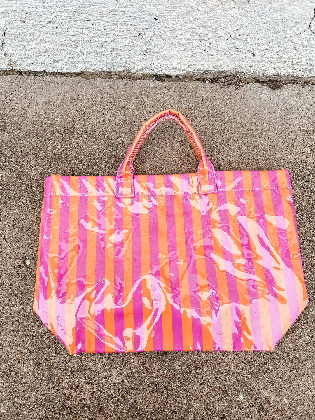 Pink and orange striped bag on a concrete surface