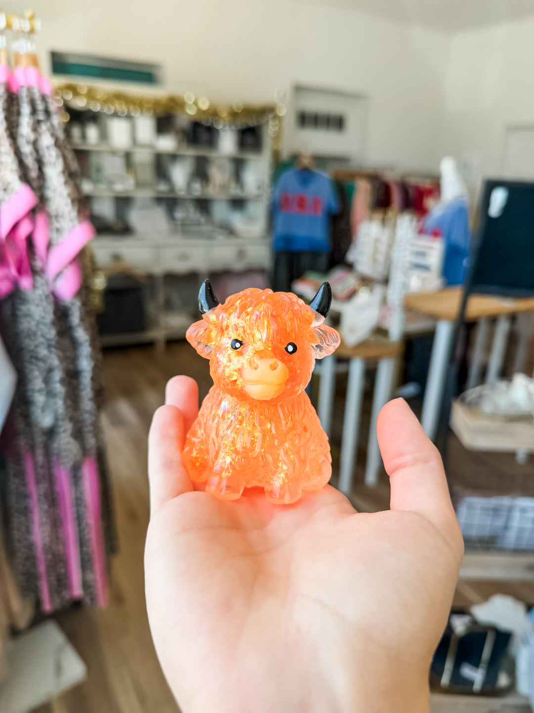 An orange translucent highland cow squishy held in a person&