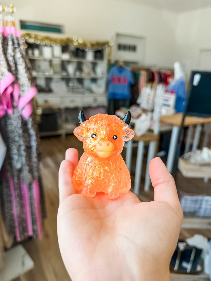 An orange translucent highland cow squishy held in a person&