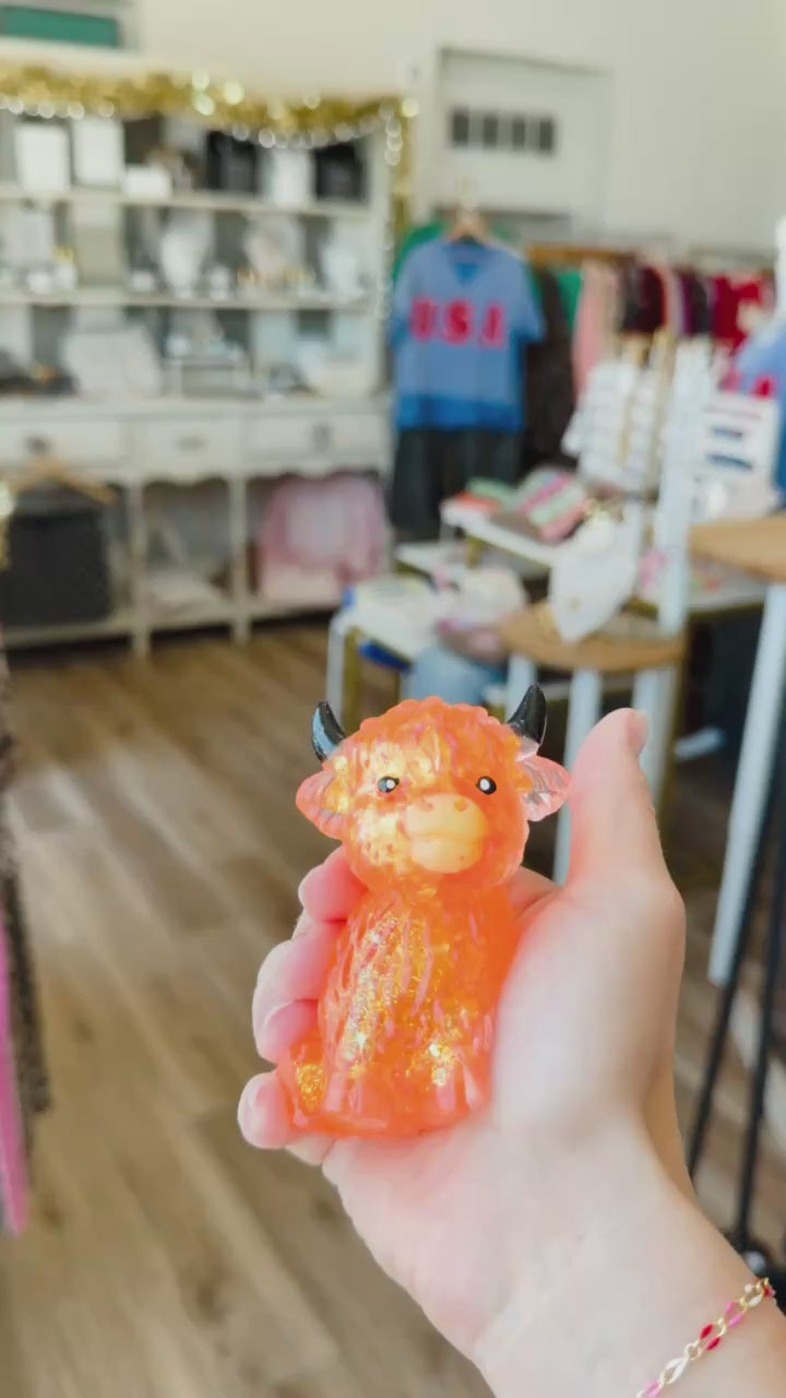 hand squeezing orange highland cow squishy