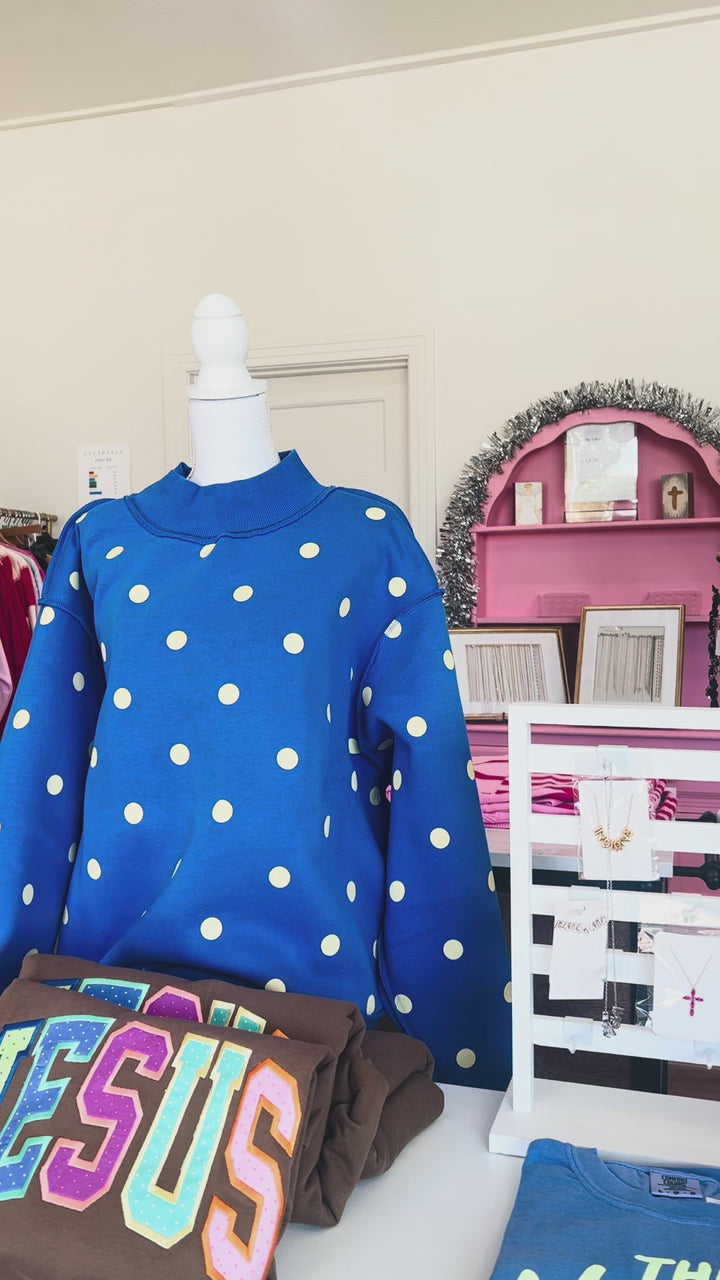 video featuring reversible blue mock neck, one side says mother across the chest in white text, the other side features white polka dots
