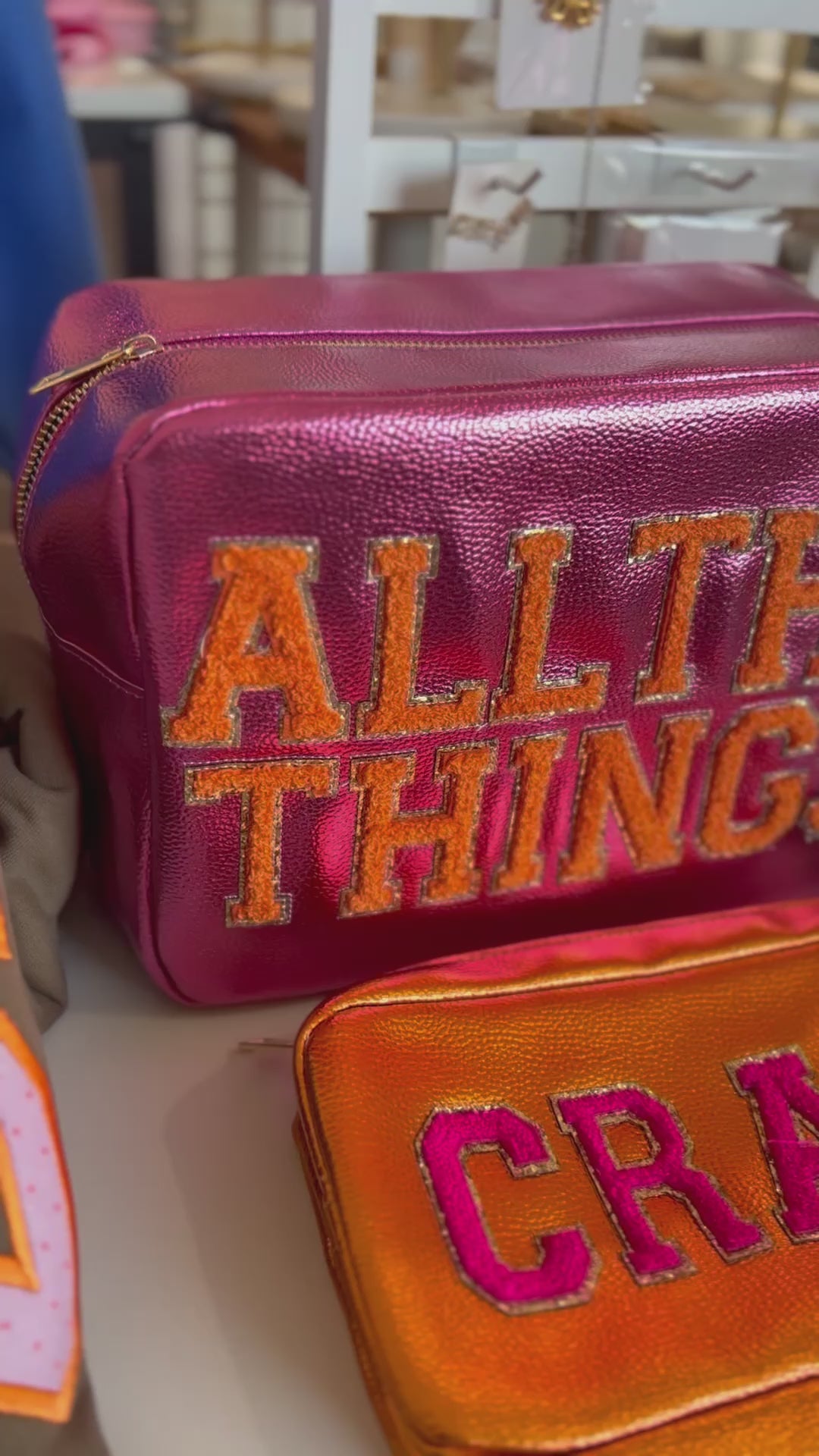 Video featuring pink cosmetic bag with varsity letter text "all the things" and an orange cosmetic bag with varsity letter text "crap"