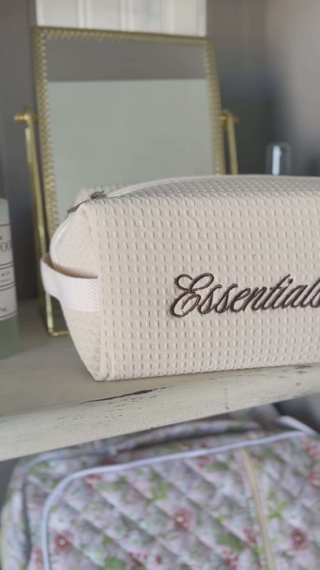 Video featuring cosmetic bag with embroidered text "essentials"