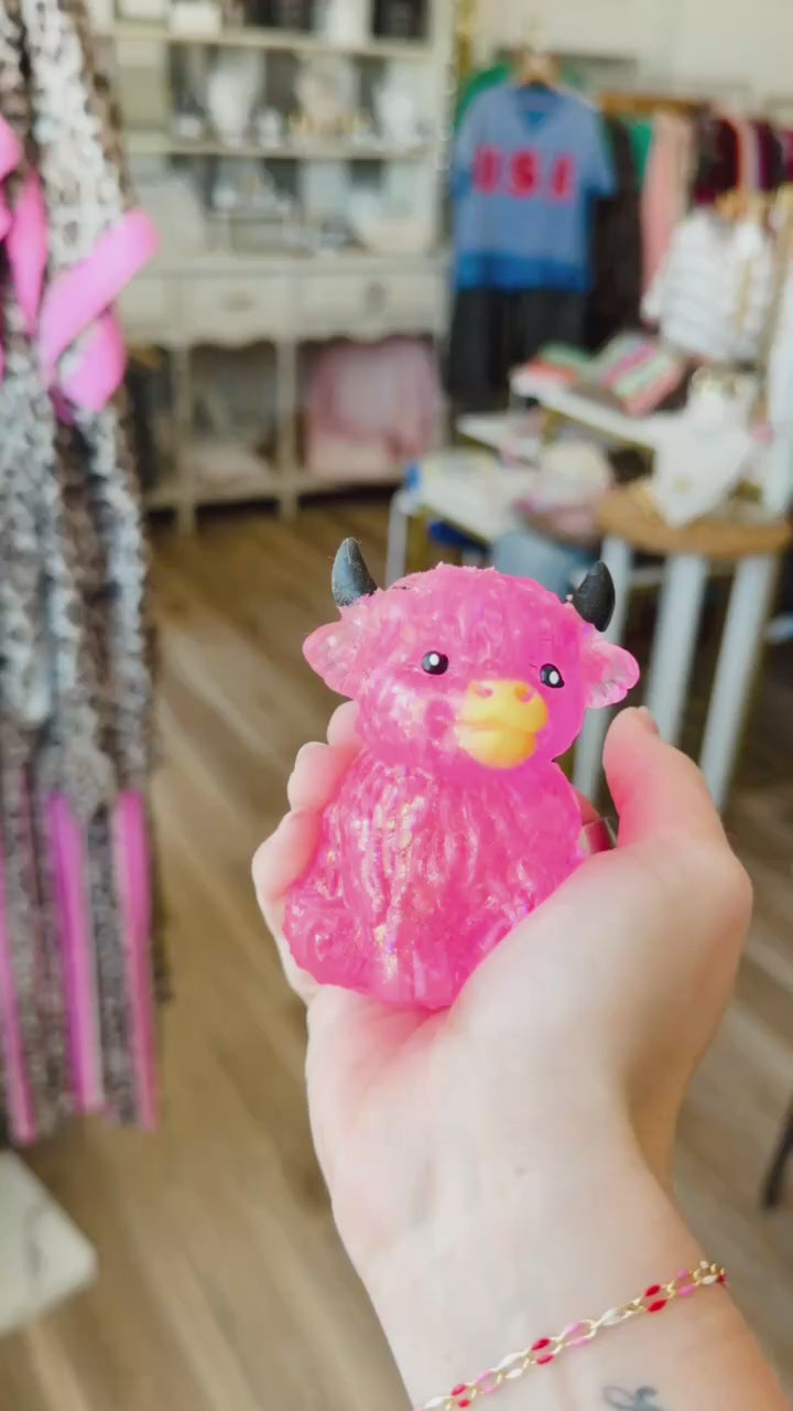 hand squeezing a pink highland cow squishy toy