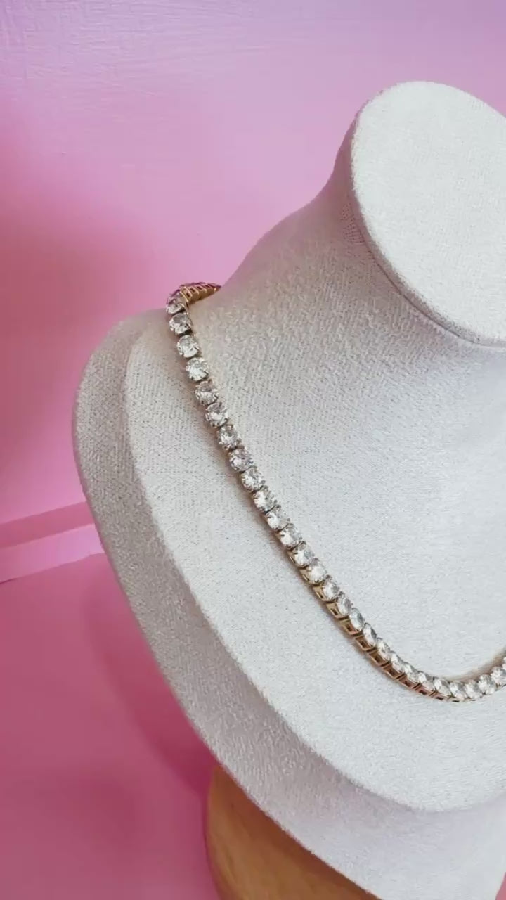 Video of silver tennis necklace on form sitting on a pink shelf 