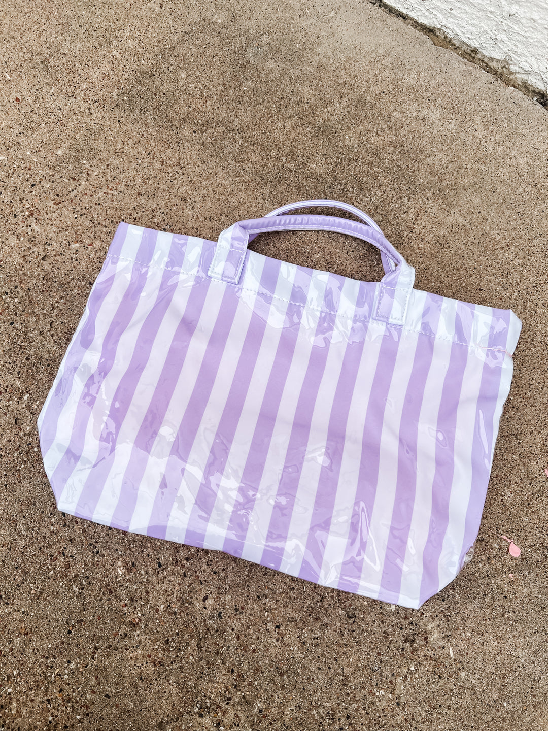 striped purple and white bag on a concrete surface