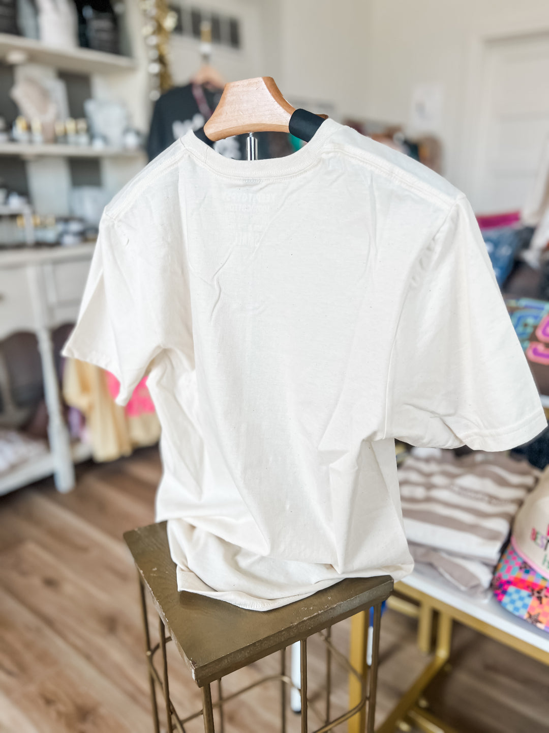 backside of cream shirt on a hanger in a room with shelves and furniture.