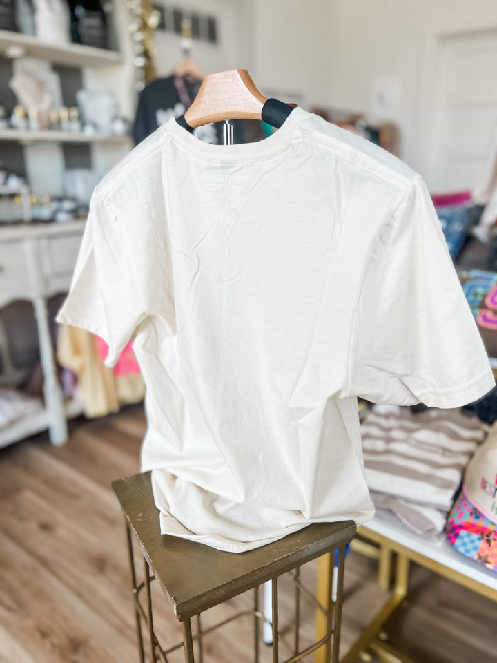 backside of cream shirt on a hanger in a room with shelves and furniture.