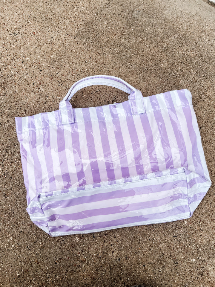 Purple and white striped bag on sandy ground