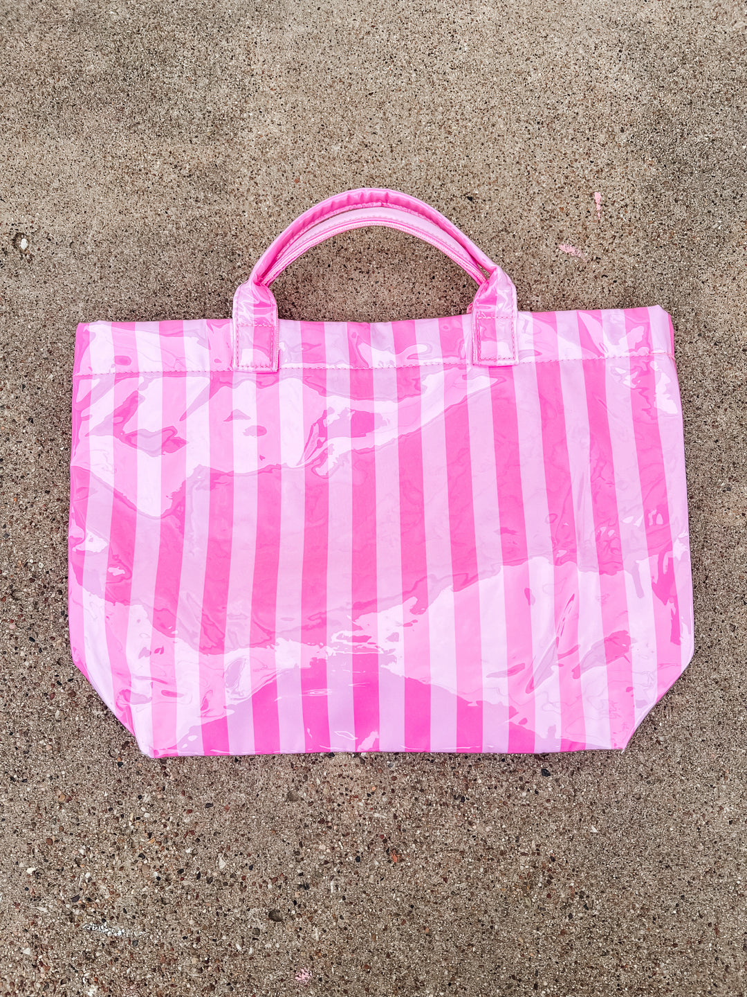 Pink and white striped bag on a concrete surface